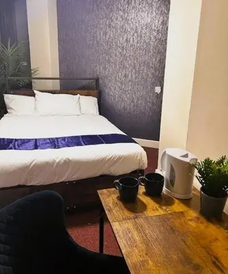 a bedroom with a bed and a wooden table with a table sidx sidx at Hillcrest Liverpool City Central in Liverpool