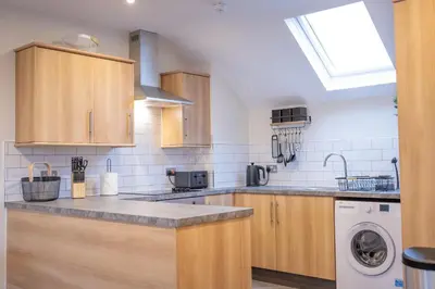 a kitchen with wooden cabinets and a washer and dryer at Lethbridge Villa 49 Apartment 3 Super Fibre WiFi, Free parking in Southport