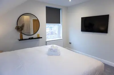 a white bedroom with a white bed with a mirror at Lethbridge Villa 49 Apartment 3 Super Fibre WiFi, Free parking in Southport