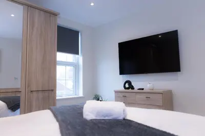 a bedroom with a bed with a television on the wall at Lethbridge Villa 49 Apartment 2 Super Fibre WiFi, free parking in Southport