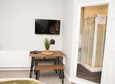 a room with a table with a television on a wall at Vance Retreat in Blackpool