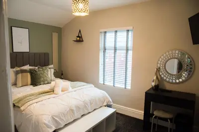 a bedroom with a bed and a mirror and a window at Vance Retreat in Blackpool