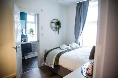 a white bedroom with a bed and a window at Vance Retreat in Blackpool