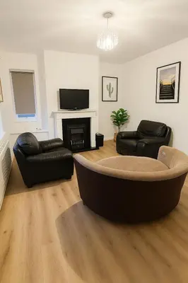 a living room with two black leather chairs and a fireplace at Prime Comfort Wigan in Ince-in-Makerfield