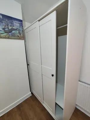 a closet with white cabinets and a glass door at Prime Comfort Wigan in Ince-in-Makerfield