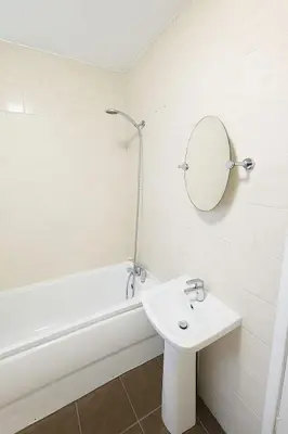a white bathroom with a sink and a bath tub at Prime Comfort Wigan in Ince-in-Makerfield