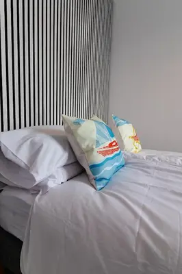 a bed with white sheets and pillows on it at Sunbeam House 3 Morecambe in Morecambe