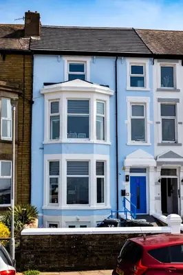 a blue house with a red car parked in front of it at Sunbeam House 3 Morecambe in Morecambe