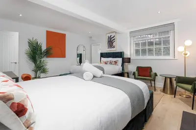 a bedroom with a large white bed and chairs at Flatzy - City Centre Mansion, Sleeps 20, 5 Baths in Liverpool