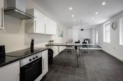 a kitchen with white cabinets and a black counter top at Blackpool Abode - Shaw Heights in Blackpool