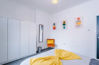 a bedroom with a bed with a yellow blanket on it at Beautiful Home In Bolton in Bolton