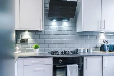 a kitchen with white cabinets and a stove top oven at Beautiful Home In Bolton in Bolton