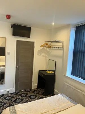 a bedroom with a desk and a mirror and a door at Shores Holiday Apartments in Blackpool
