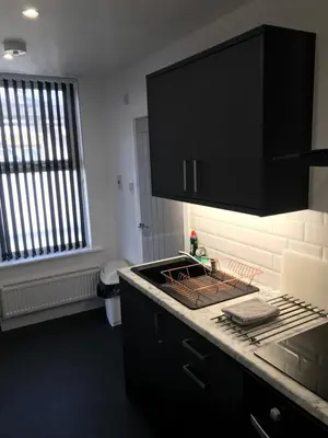 a kitchen with black cabinets and a black counter top at Shores Holiday Apartments in Blackpool