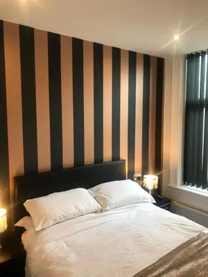 a bedroom with a bed with a striped wall at Shores Holiday Apartments in Blackpool
