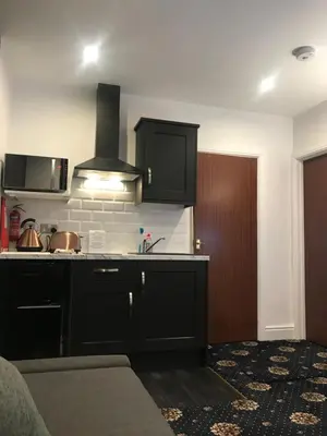 a kitchen with black cabinets and a sink at Shores Holiday Apartments in Blackpool