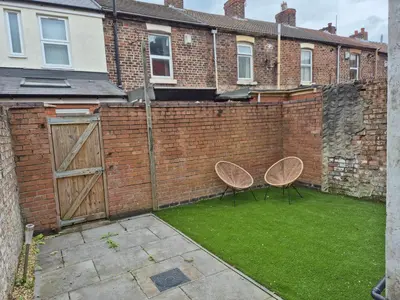 a brick wall with two chairs in a yard at House next to Anfield Stadium, Goodison Park in Liverpool