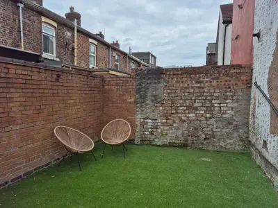 two chairs sitting in the courtyard of a brick wall at House next to Anfield Stadium, Goodison Park in Liverpool