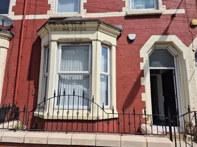 a red brick building with a window and a balcony at House next to Anfield Stadium, Goodison Park in Liverpool