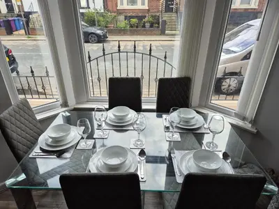 a dining room table with chairs and plates and glasses at House next to Anfield Stadium, Goodison Park in Liverpool