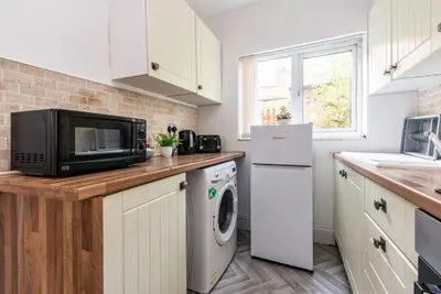 a kitchen with a microwave and a washer and dryer at Spacious 4-Bedroom Home Close to Liverpool City Centre in Liverpool
