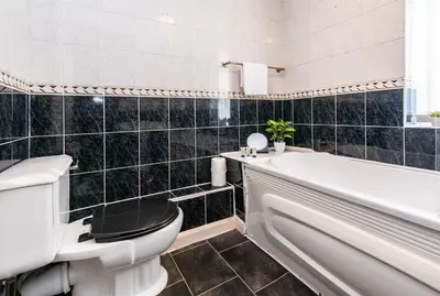 a bathroom with a toilet and a tub and a sink at Spacious 4-Bedroom Home Close to Liverpool City Centre in Liverpool