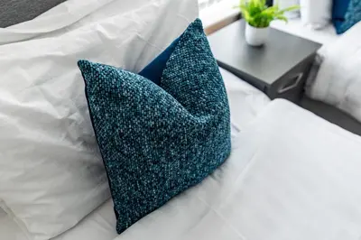 two blue pillows sitting on a white bed at Spacious 4-Bedroom Home Close to Liverpool City Centre in Liverpool