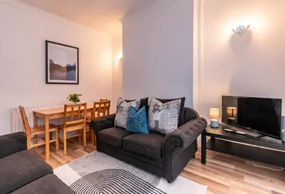 a living room with a couch and a television and a table at Spacious 4-Bedroom Home Close to Liverpool City Centre in Liverpool