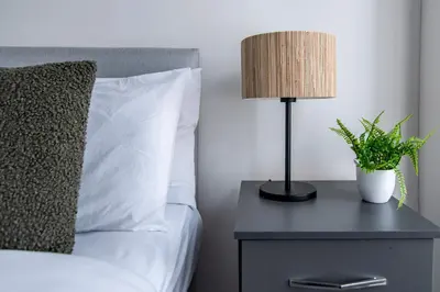 a bed with a nightstand with a lamp and a plant at Spacious 4-Bedroom Home Close to Liverpool City Centre in Liverpool