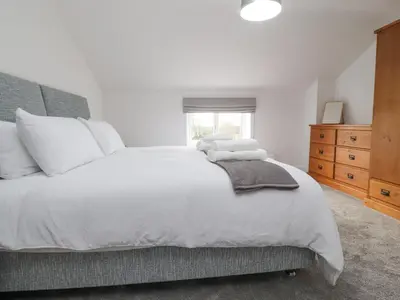 a bedroom with a large white bed and a dresser at Apple Tree Cottage in Preston