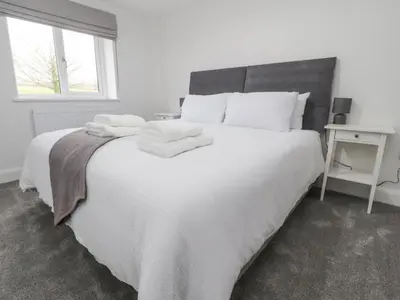 a bedroom with a large white bed with towels on it at Apple Tree Cottage in Preston