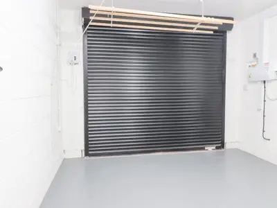 a garage door in a white room with a bathroom at Apple Tree Cottage in Preston