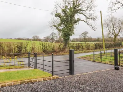 a gate on a road next to a field at Apple Tree Cottage in Preston