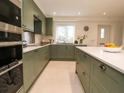 a kitchen with green cabinets and a sink at Pear Tree Cottage in Preston