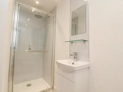 a white bathroom with a shower and a sink at Pear Tree Cottage in Preston