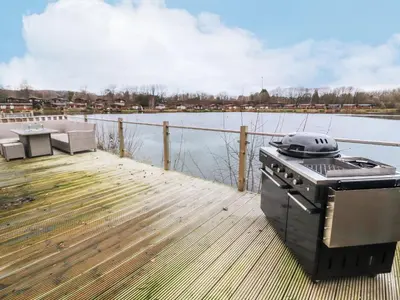 a grill sitting on a dock next to a body of water at 12A Lake Escape in Carnforth