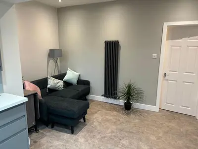 a living room with a black couch and a chair at Stumps and Bails Families and contractors welcome in Ormskirk