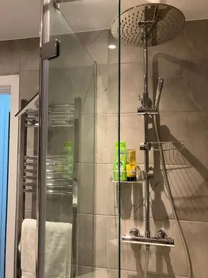 a bathroom with a shower with a glass door at Stumps and Bails Families and contractors welcome in Ormskirk