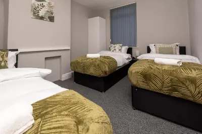 a room with two beds with gold sheets at Spacious Central Liverpool Home in Liverpool