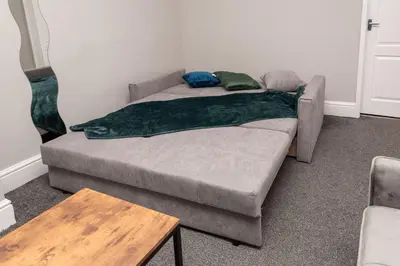 a bed with a green blanket on it in a room at Spacious Central Liverpool Home in Liverpool