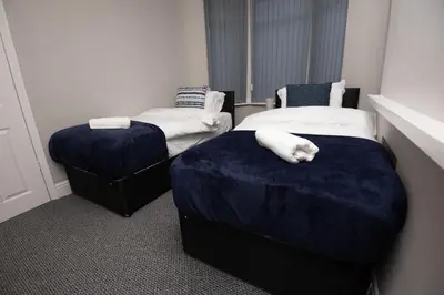 two beds in a room with blue and white sheets at Spacious Central Liverpool Home in Liverpool