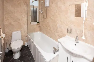 a bathroom with a tub and a toilet and a sink at Spacious Central Liverpool Home in Liverpool