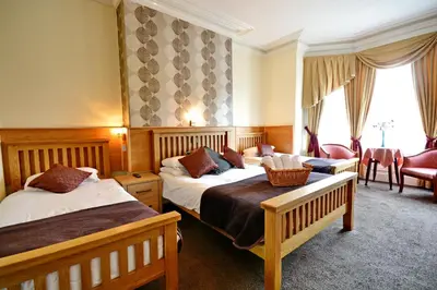 a hotel room with two beds and a sitting area at The Derby Hotel in Blackpool