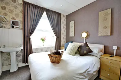 a bedroom with a bed and a sink and a window at The Derby Hotel in Blackpool