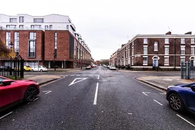 an empty city street with parked cars and buildings at Stunning Centrally Located Studio Apt in Liverpool