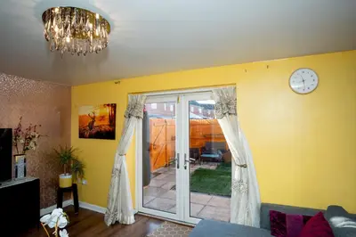 a living room with a clock and a sliding glass door at 1 minute walk to Liverpool Stadium Free Private Parking, Anfield Liverpool Entire House in Liverpool