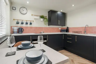 a kitchen with black cabinets and a table with wine glasses at The Lodge in Woodplumpton