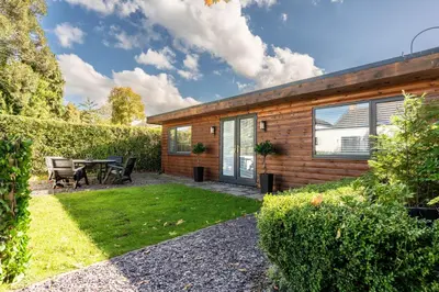 a wooden house with a table and a patio at The Lodge in Woodplumpton