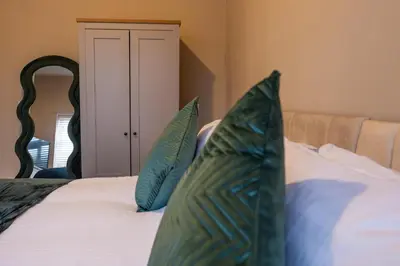 a bedroom with a bed with blue and green pillows at Cosy Home 2 Bedroom House Birkdale in Southport