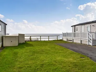 a grassy yard next to a building and the ocean at Ocean View in Lancaster